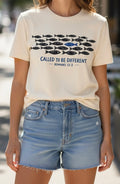 Called to be different. Romans 12:2. One fish swimming the other direction. Cream T-shirt with black and blue print.