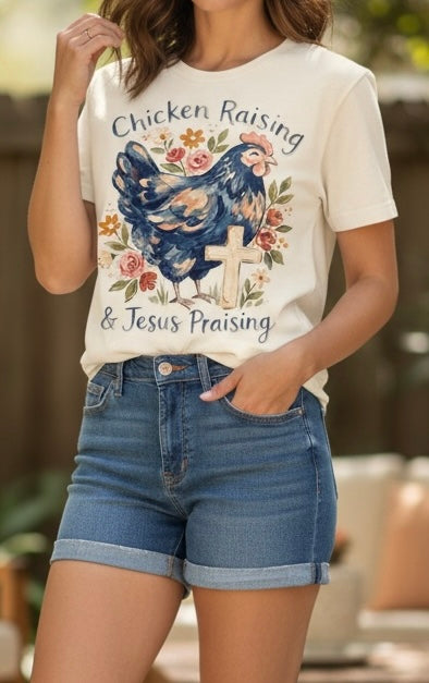 Woman wearing a t-shirt with a graphic of a rooster and text 'Chicken Raising & Jesus Praising'.