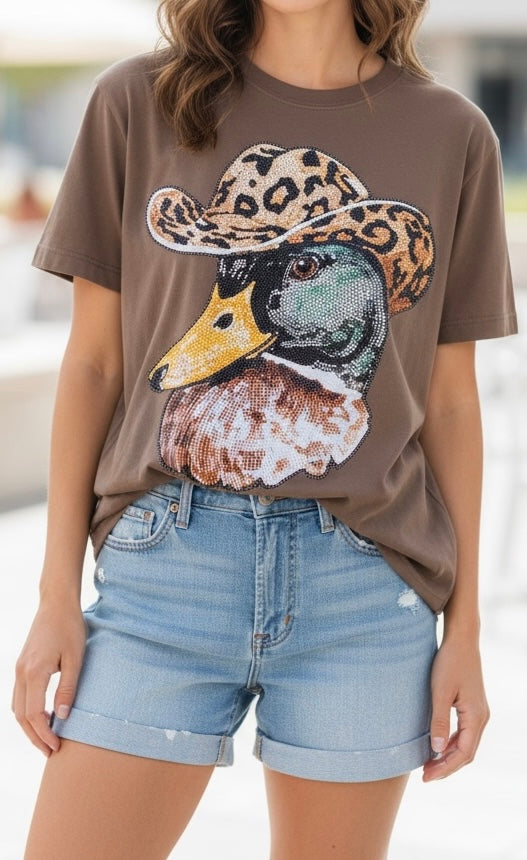 Person wearing a brown t-shirt with a duck graphic and leopard print hat, paired with light blue denim shorts.