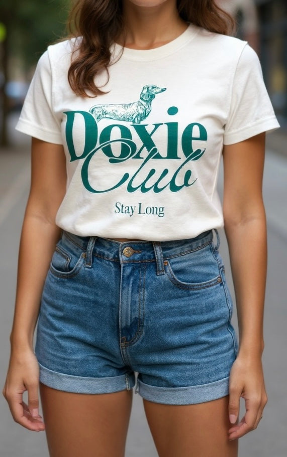 Person wearing a white t-shirt with 'Doxie Club Stay Long' text and blue shorts.