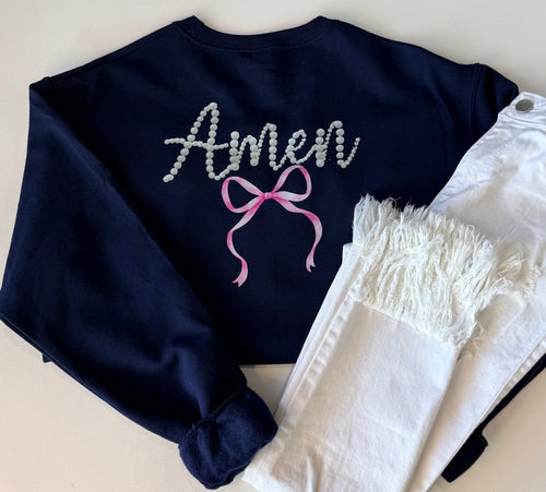 Navy blue sweatshirt with 'Amen' and a pink bow design on a light background